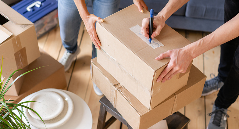 Close Up Of Hand Packing Cardboard Box, Concept Moving House. Yo