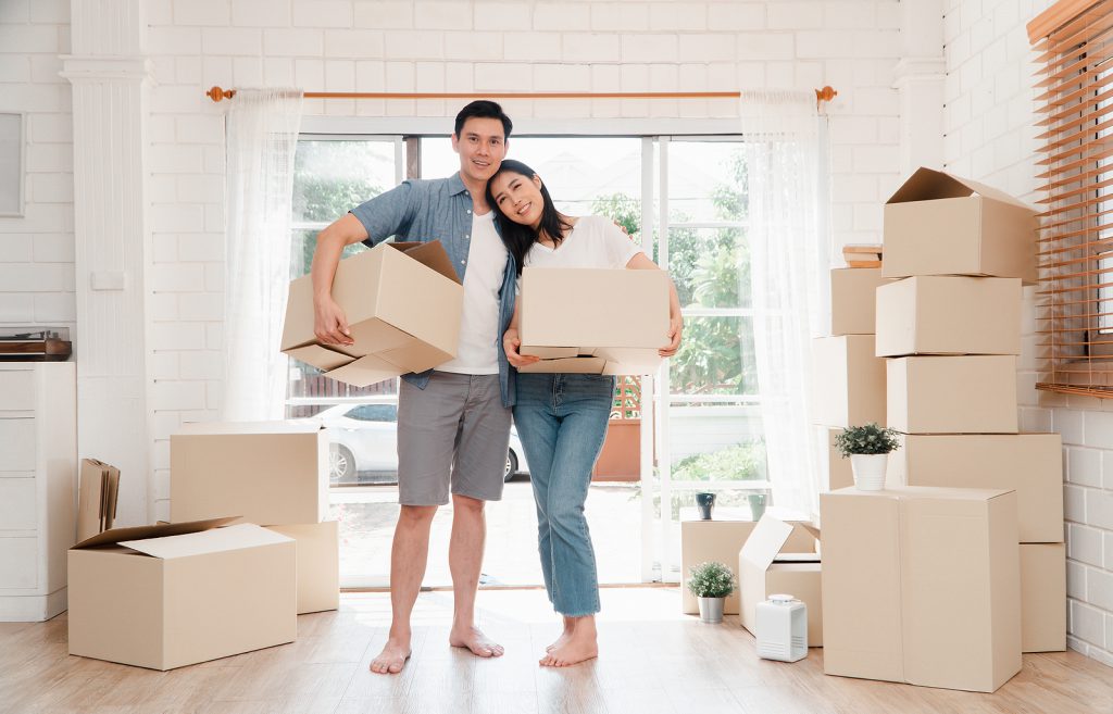 Un jeune couple heureux transporte des cartons et marche depuis le