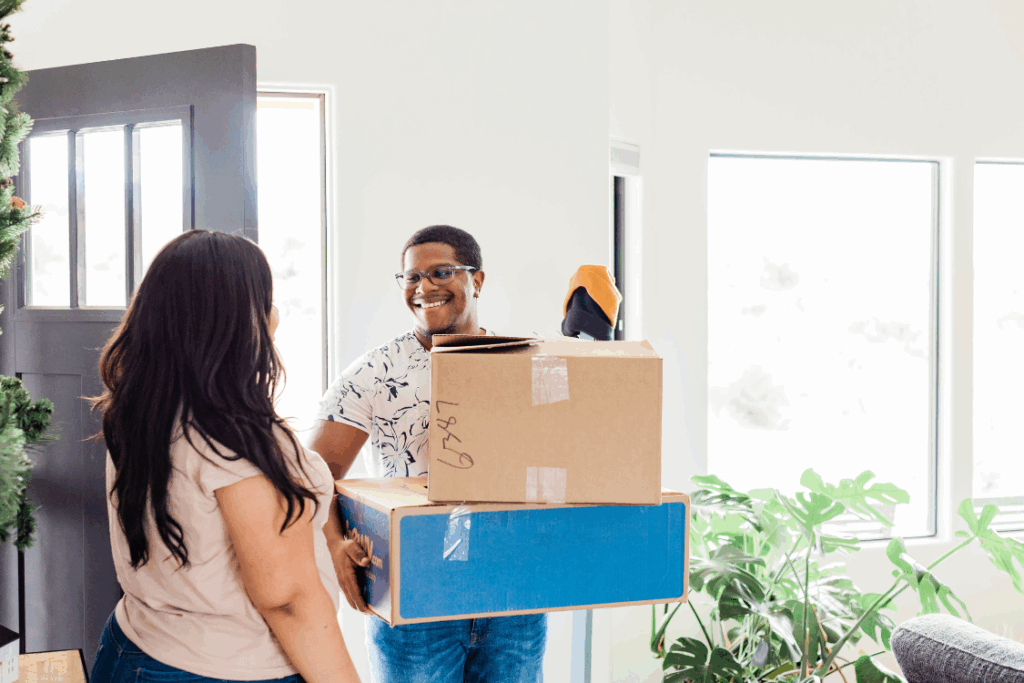 A man is carrying two boxes while smiling at a woman across from him.