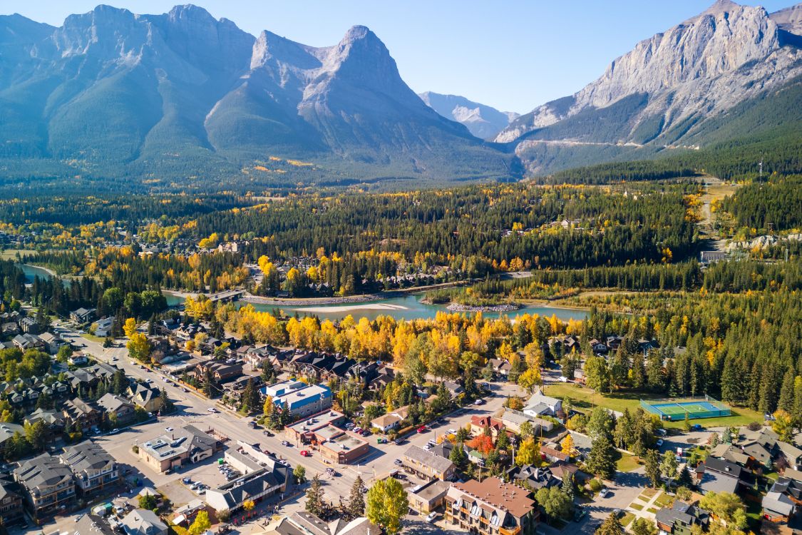 Vue aérienne de la ville de Canmore nichée dans une vallée montagneuse aux couleurs automnales et traversée par une rivière
