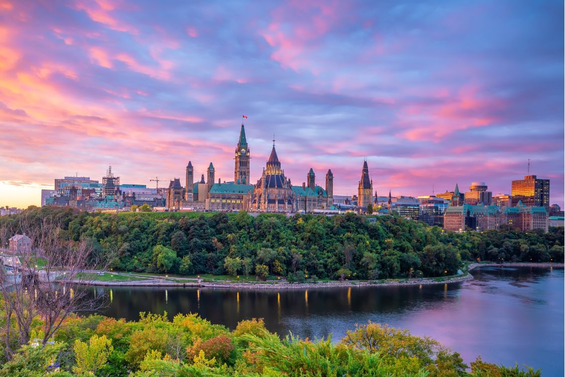 La Colline du Parlement à Ottawa au coucher du soleil, avec la Tour de la Paix et la vue sur le fleuve.