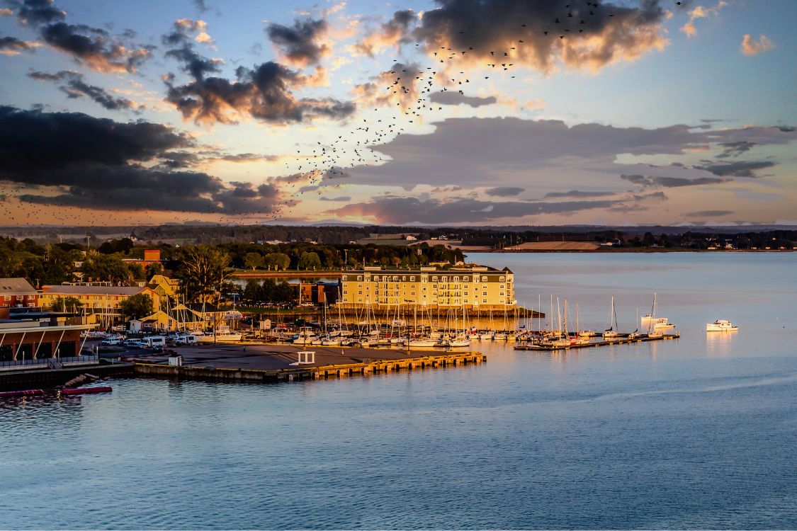 Le port au coucher du soleil sur l'Île-du-Prince-Édouard, avec ses voiliers, ses quais et ses bâtiments le long d'un front de mer calme.