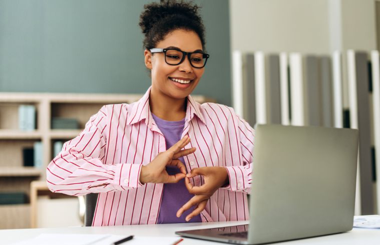Une femme souriante portant des lunettes fait un signe OK de la main.