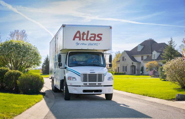 Un camion Atlas est stationné devant une maison, prêt à charger ou décharger des biens.