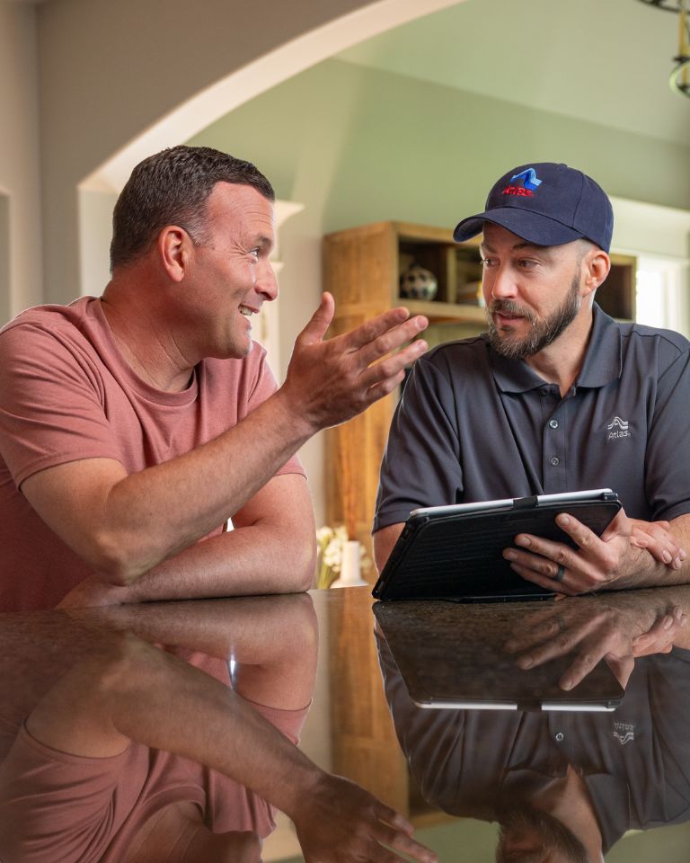 Two men engaged in conversation at a kitchen table, surrounded by a warm and inviting home environment.